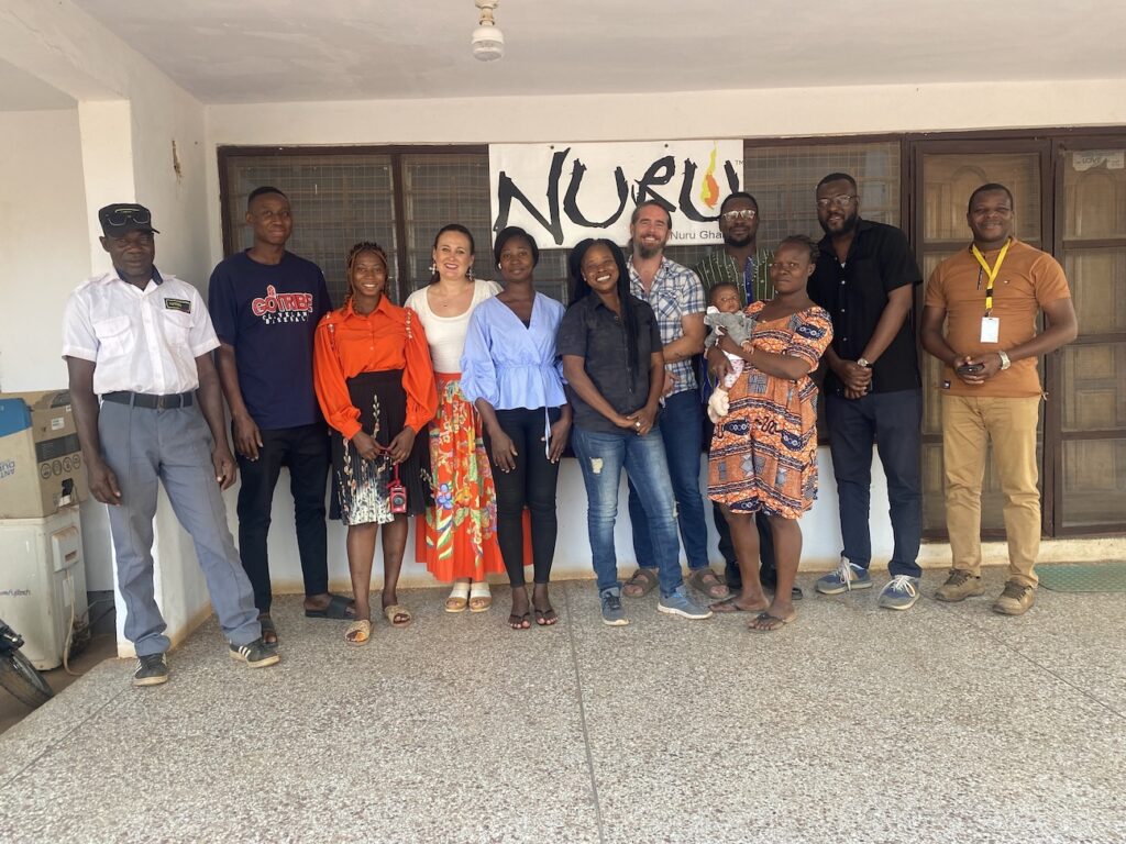 group of people standing outside in front of "Nuru Ghana" sign